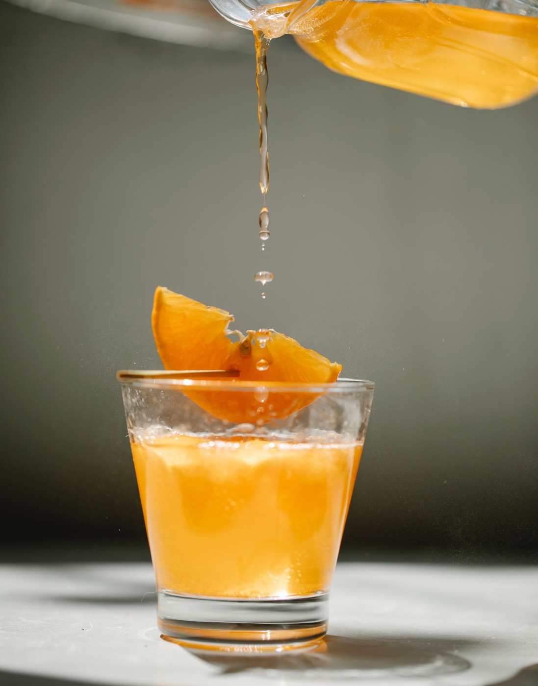 Una bibita all'arancia viene versata in un bicchiere, guarnito con una fetta d'arancia